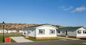 Row of modern mobile homes with brick foundations under a clear blue sky.